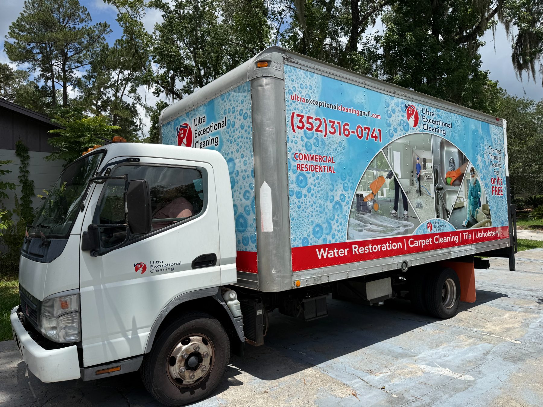 Ultra Exceptional Cleaning service truck with blue and red wrap parked in driveway