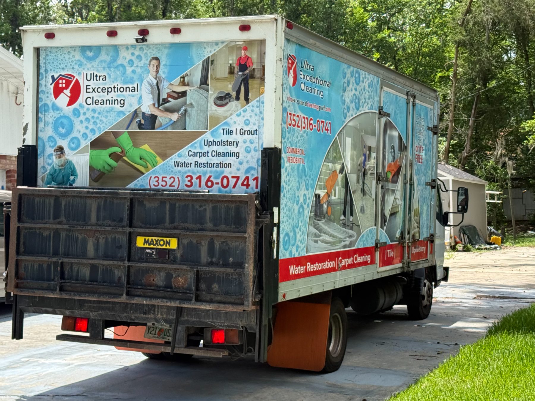 Ultra Exceptional Cleaning service truck with blue wrap displaying cleaning services and phone number parked on residential driveway